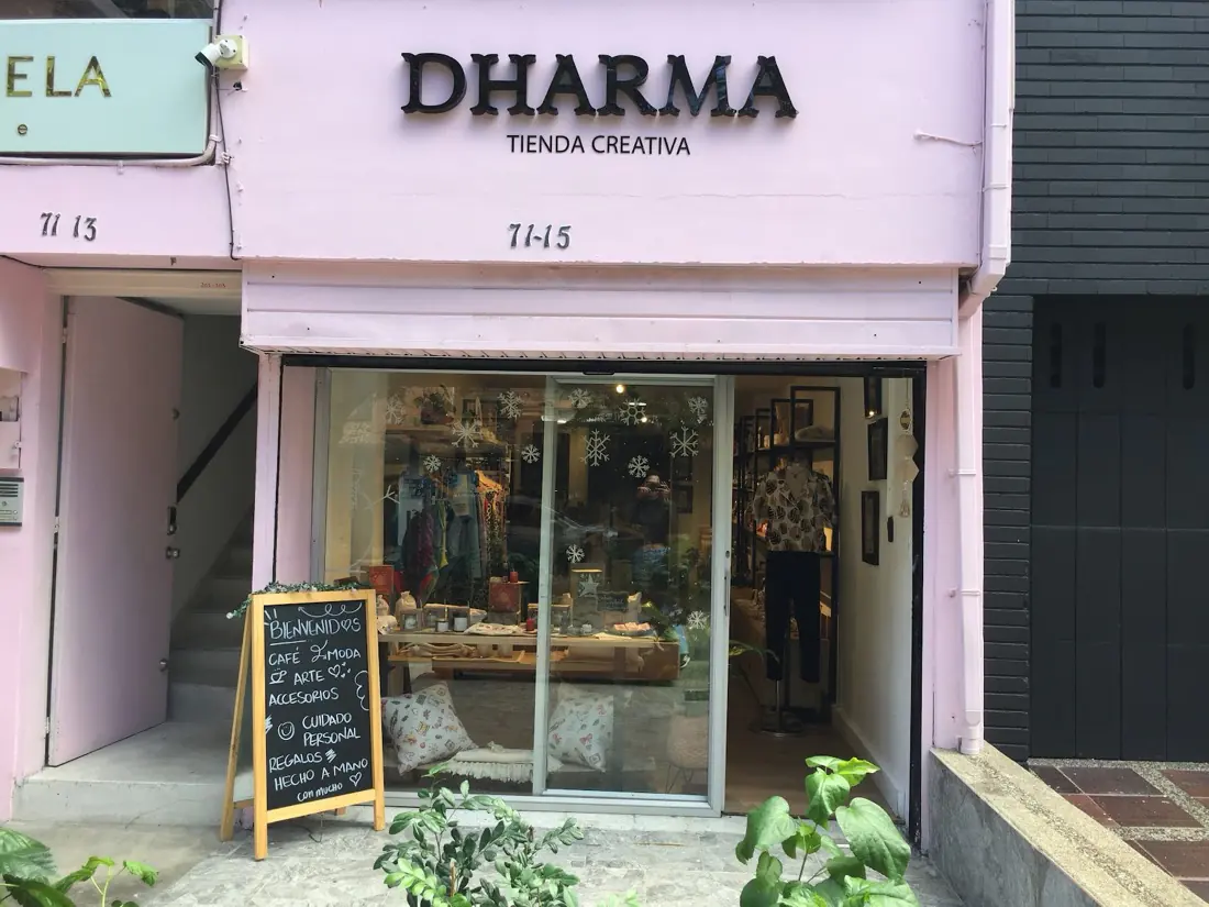 Fachada lila de Dharma Tienda Creativa con su aviso, la vitrina y un tablero de bienvenida